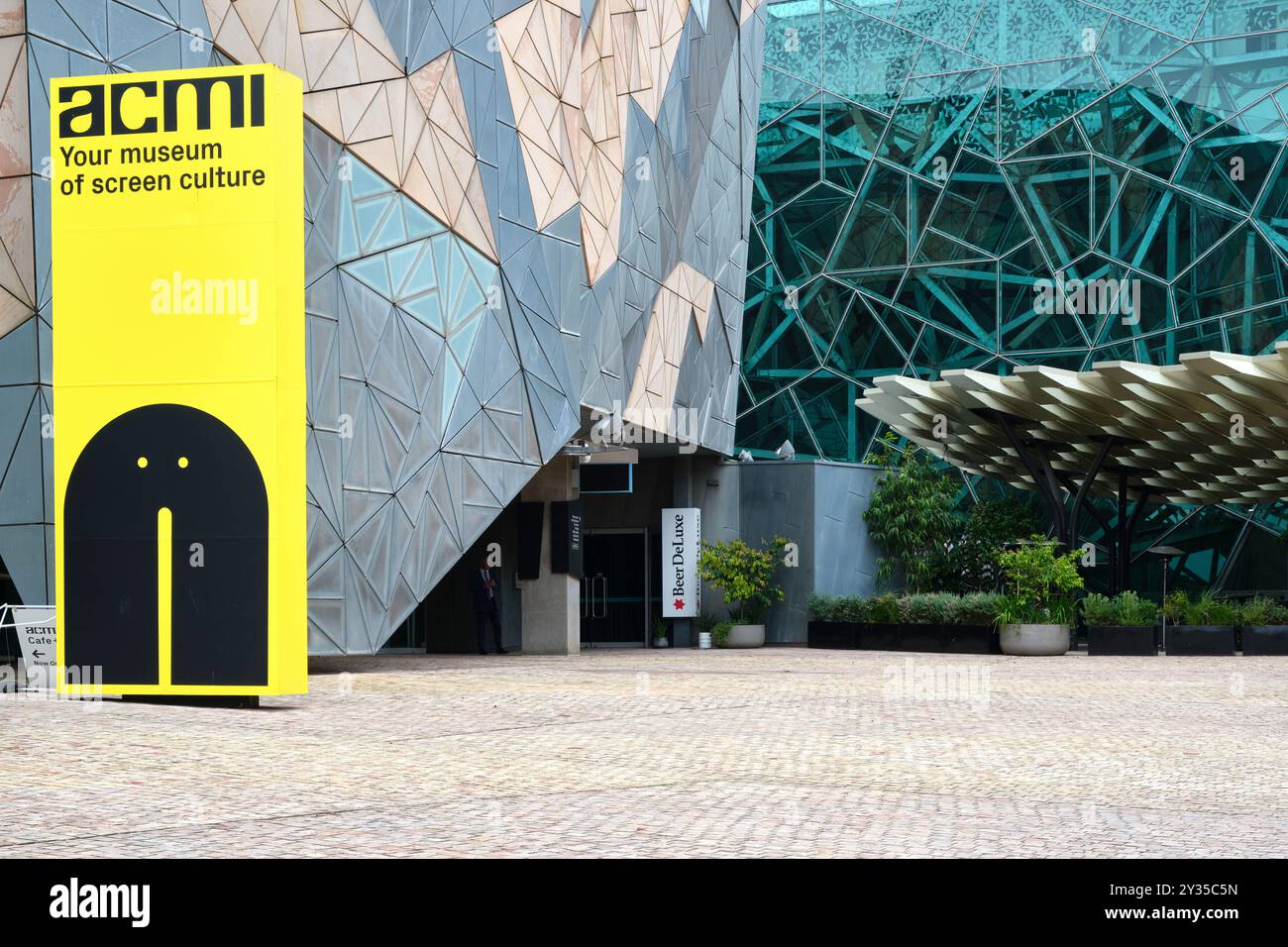 Un cartello che pubblicizza ACMI, il museo nazionale australiano della cultura dello schermo, tra i moderni edifici architettonici di Federation Square a Melbourne. Foto Stock