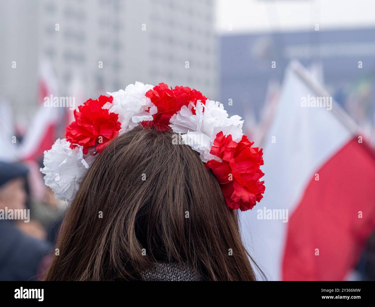 Primo piano sulla testa di una ragazza con corona di fiori bianchi e rossi durante la manifestazione patriottica. Varsavia, Polonia. Sfondo sfocato. Foto Stock