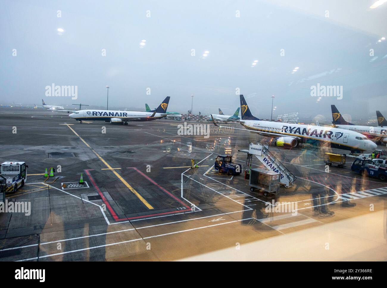 I viaggiatori delle compagnie aeree si riflettono sulla finestra, mentre fanno la coda per un volo Ryanair all'aeroporto di Dublino, Irlanda. Foto Stock