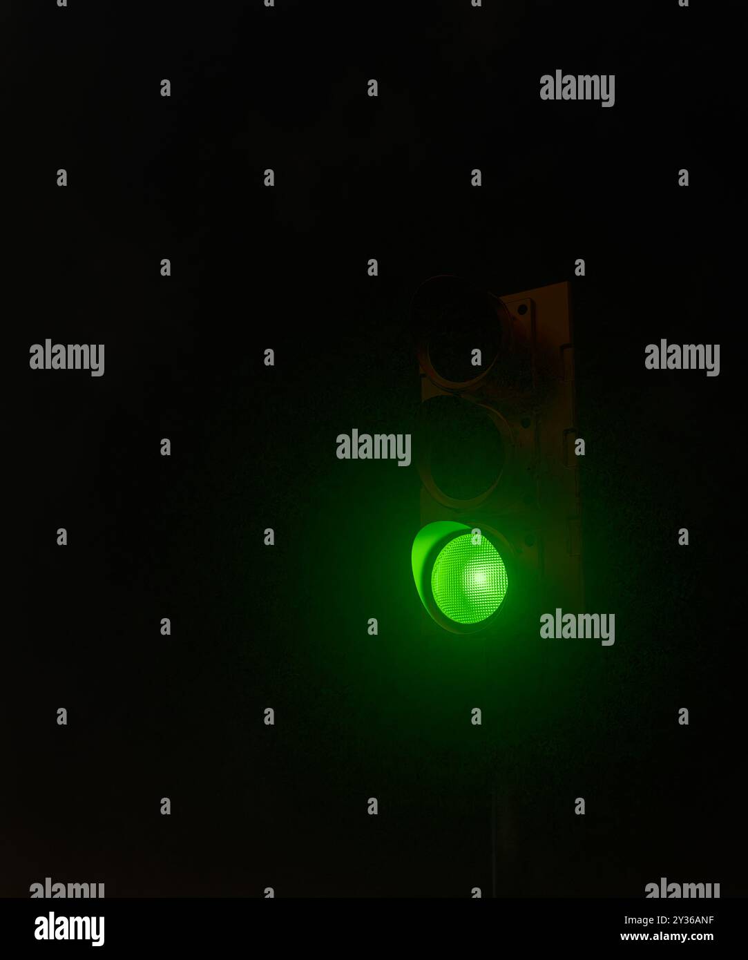 Semaforo con luce verde accesa di notte. Una classica icona di rilascio e avanzamento perfetta per progetti relativi al traffico, alla sicurezza e al concetto di autorizzazione Foto Stock