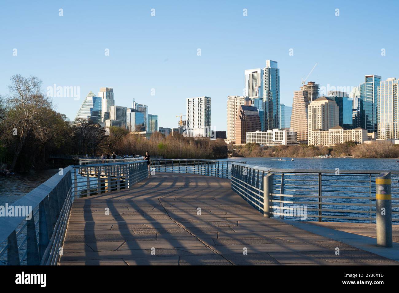 Austin, Texas - 22 febbraio 2024: Città di Austin, Texas, con persone sul percorso all'aperto lungo il fiume con edifici dello skyline sullo sfondo. Foto Stock