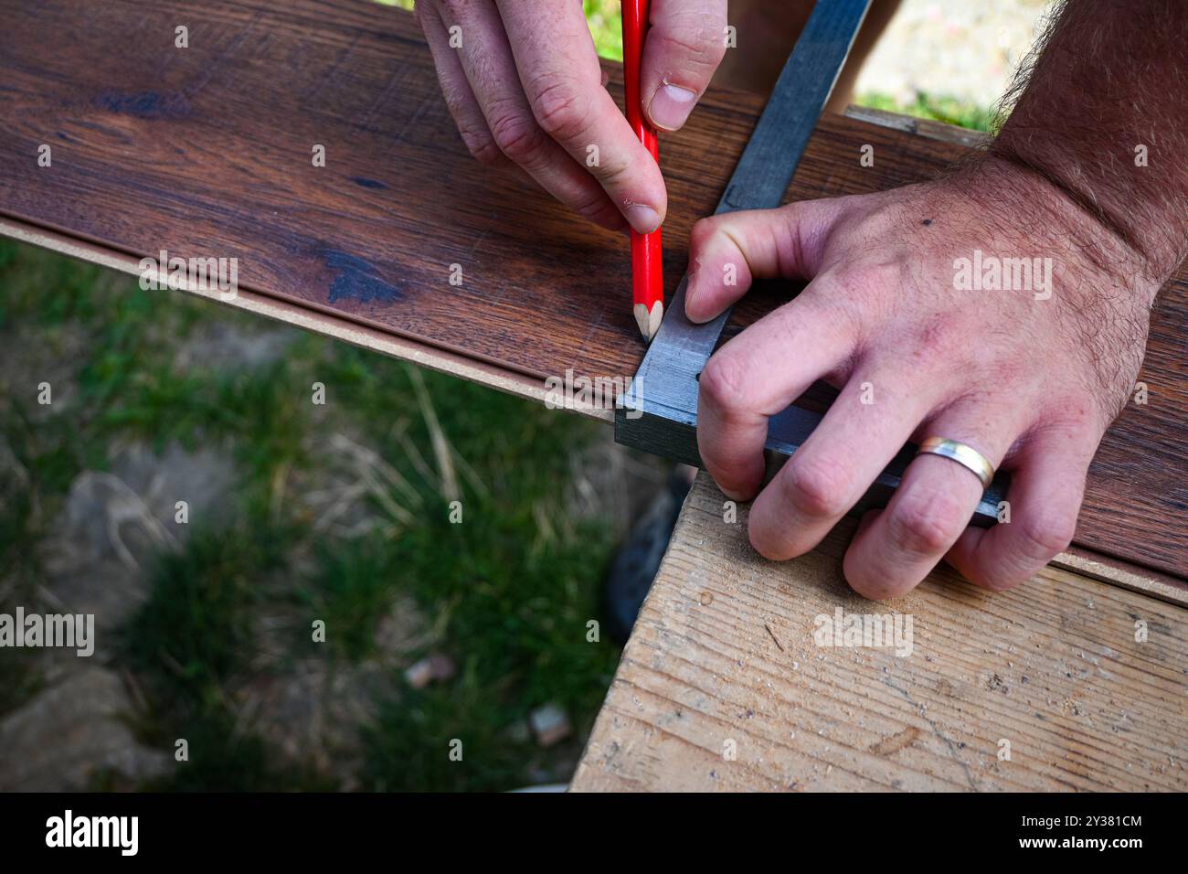 Operaio edile che utilizza un quadrato da falegname per contrassegnare una tavola di legno con una matita. Foto Stock