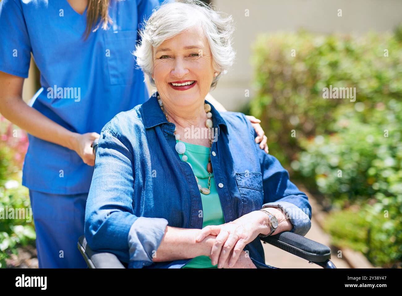 Anziani, donna e sedia a rotelle con ritratto in giardino a casa di riposo per comfort, riabilitazione o assistenza sanitaria. Infermiere, operatore sanitario e. Foto Stock