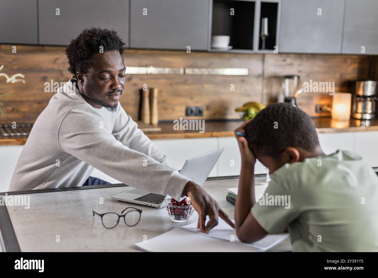 Il padre afroamericano aiuta a fare i compiti a suo figlio sconvolto Foto Stock