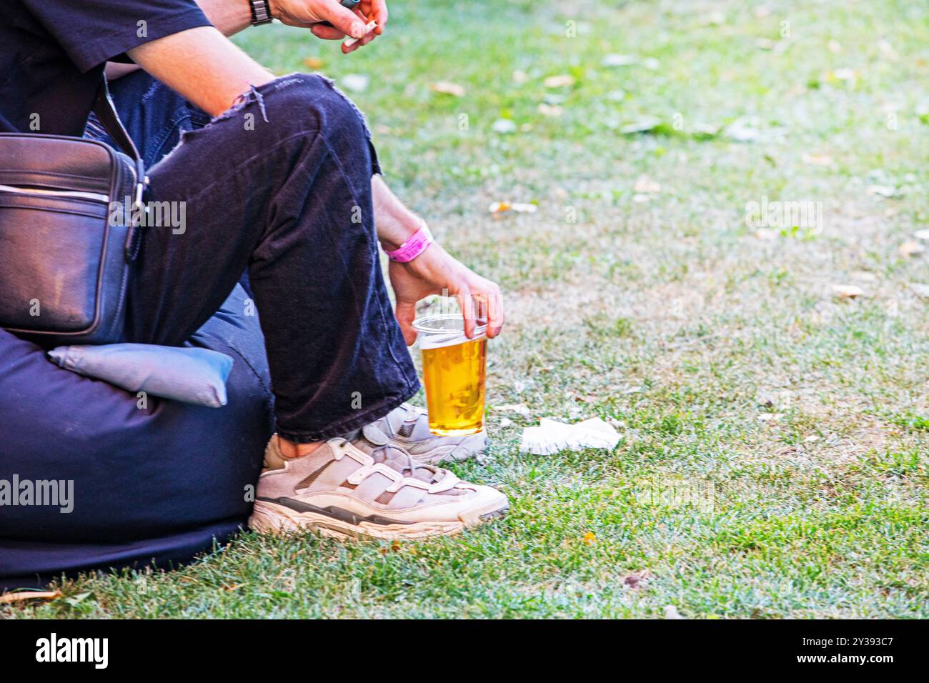 tenere un bicchiere usa e getta con birra e sigaretta durante un picnic. Spuntino Foto Stock