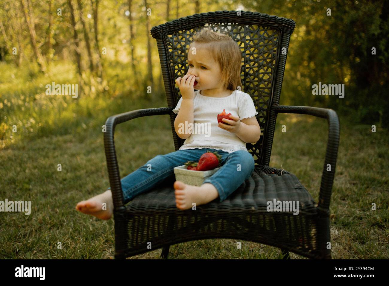 Il bambino mangia un cestino di fragole all'aperto Foto Stock