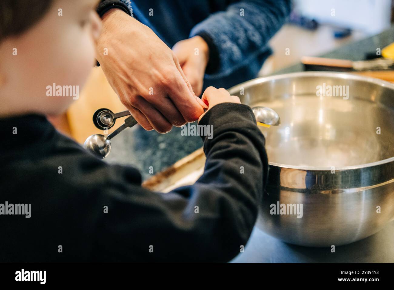 Primo piano di un bambino e di un adulto che misurano gli ingredienti Foto Stock
