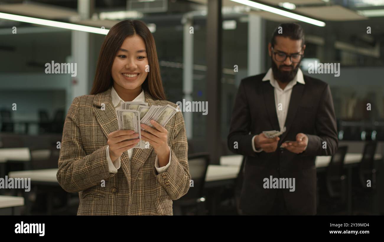 Disparità salariale problema di pagamento salario disuguaglianza salario donna felice asiatica ricca business girl donna d'affari tenere grandi soldi ufficio femminile triste indiano arabo Foto Stock