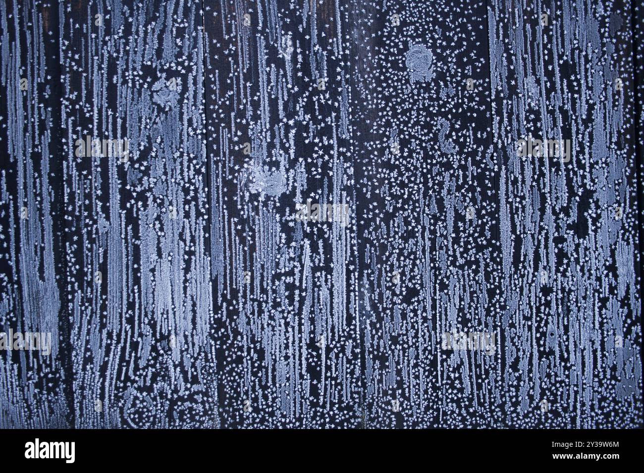 Fiocchi di neve, fiori di neve e ghiaccio, pittura di neve su recinzione scura. Sfondo invernale con texture ghiacciata. Foto invernale. Foto Stock