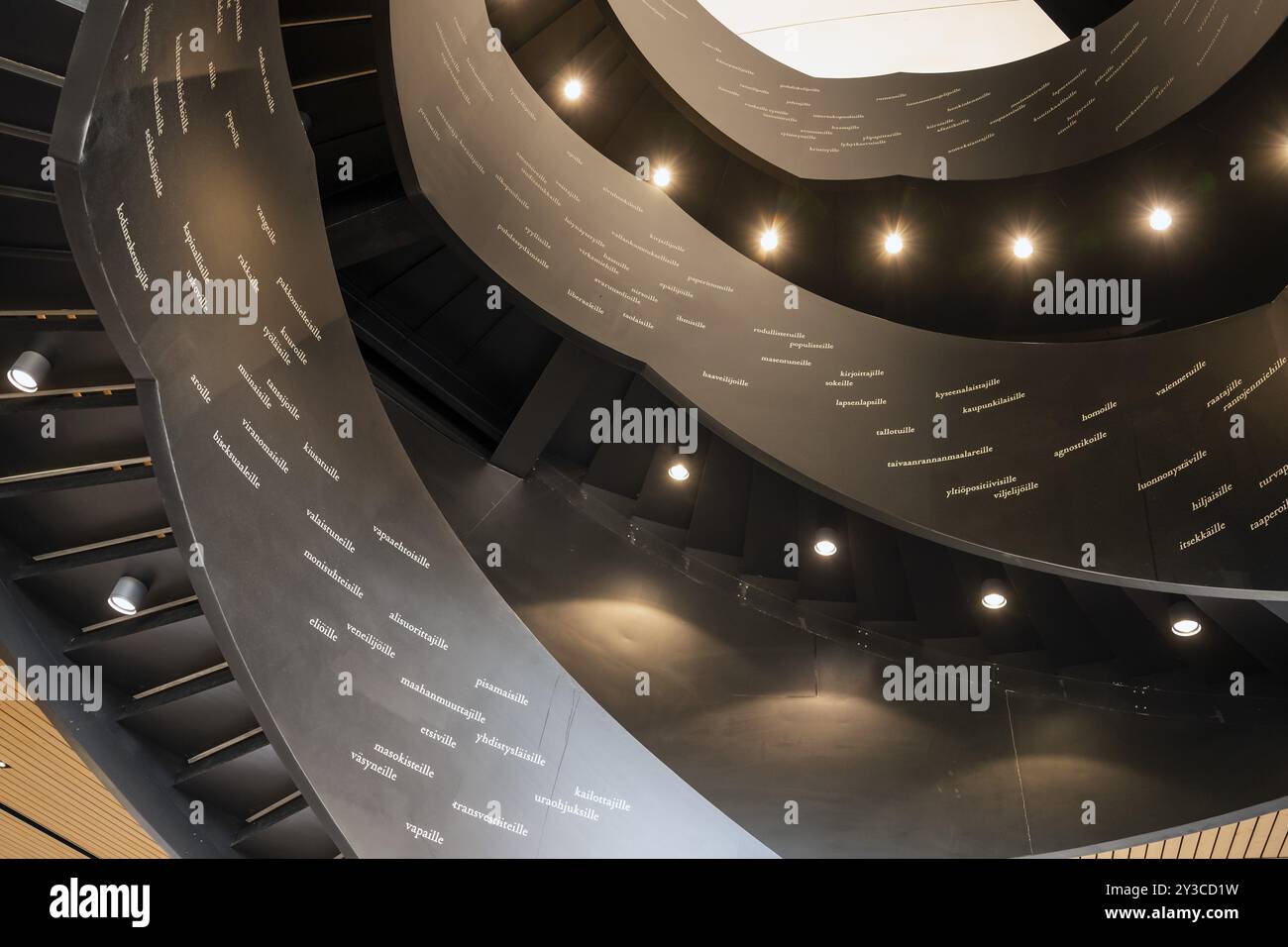 Scala a chiocciola stampata con parole finlandesi, Biblioteca centrale e Centro culturale Oodi, progettata da ala Architects, Helsinki, Finlandia, Europa Foto Stock