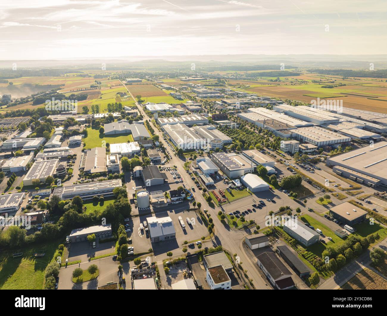 Una vista a volo d'uccello di una zona industriale con numerosi edifici industriali e campi vicini sotto un cielo limpido, la zona industriale Wolfsberg, Nagold, Foto Stock