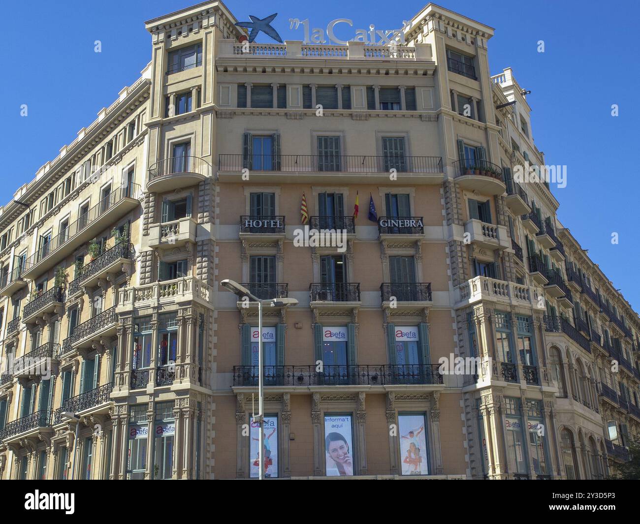 Edificio urbano con un hotel e pubblicità la Caixa, diversi balconi e bandiere blu, barcellona, Mar mediterraneo, spagna Foto Stock