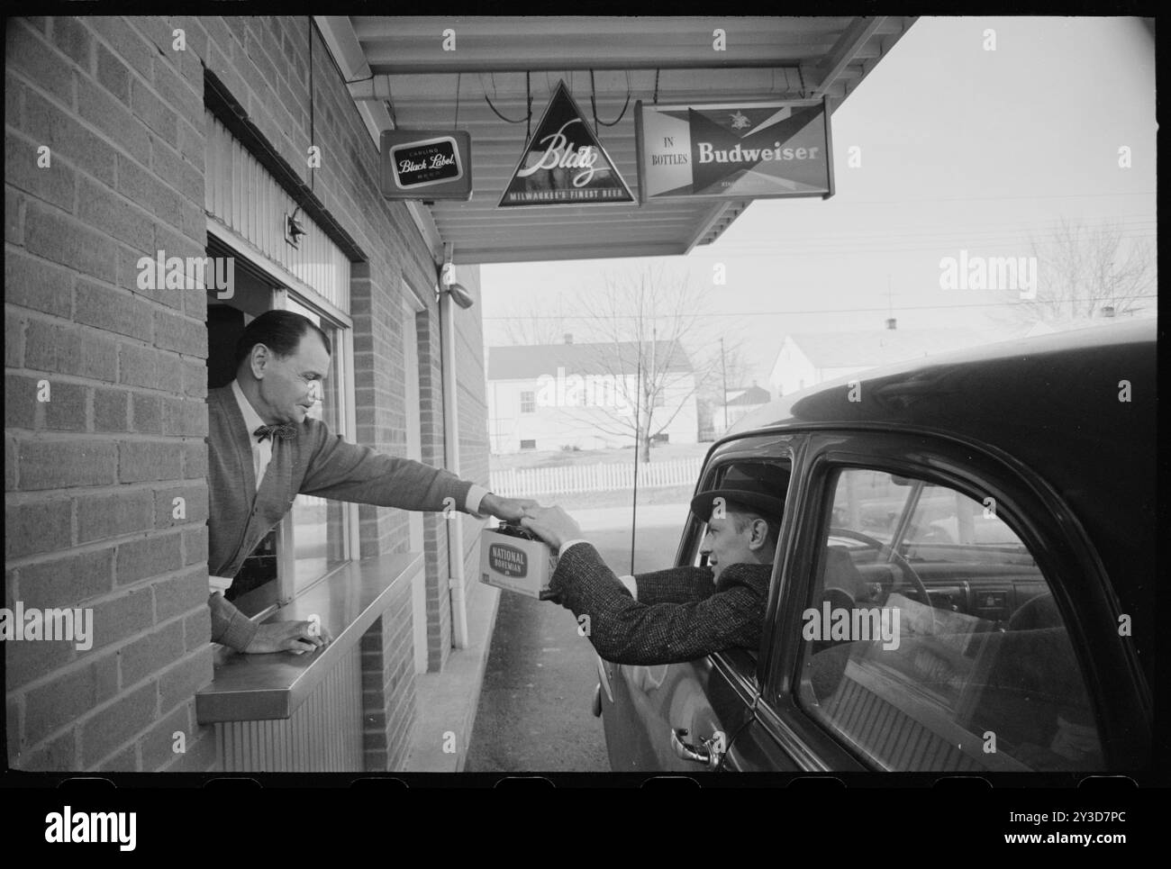 Uomo al finestrino del drive-thru che consegna un cartone di birra nazionale bohémien al cliente in un'auto, nessuna sede, 4 febbraio 1960. Foto di Marion S Trikosko/U S News e World Report Magazine Fotografia Foto Stock