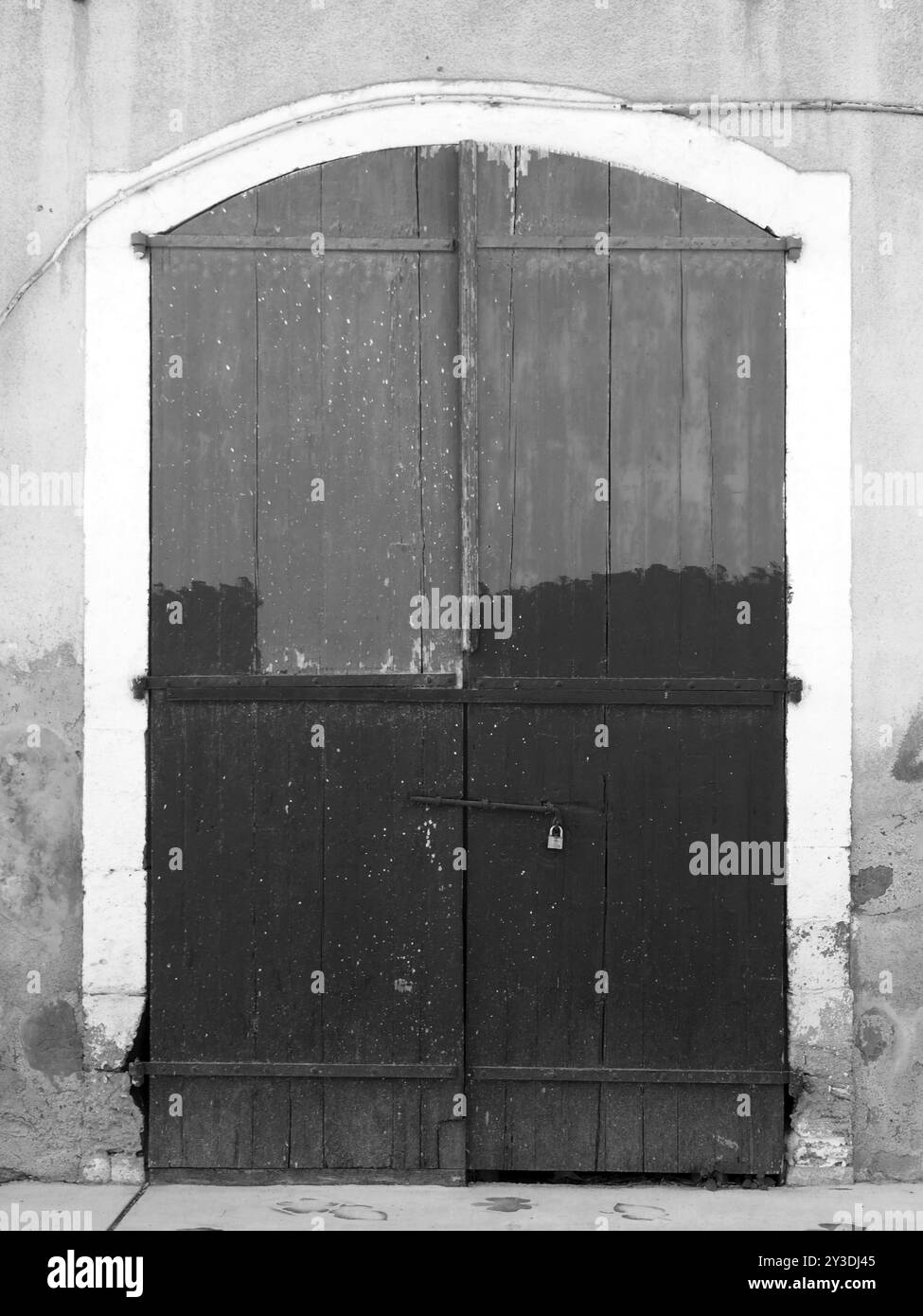 Immagine monocromatica di vecchie porte chiuse in legno su una casa vuota abbandonata con vernice irregolare Foto Stock