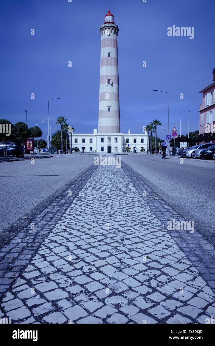 Faro maestoso a Praia da barra, Aveiro - Faro Nautico contro il sentiero acciottolato e il cielo blu Foto Stock