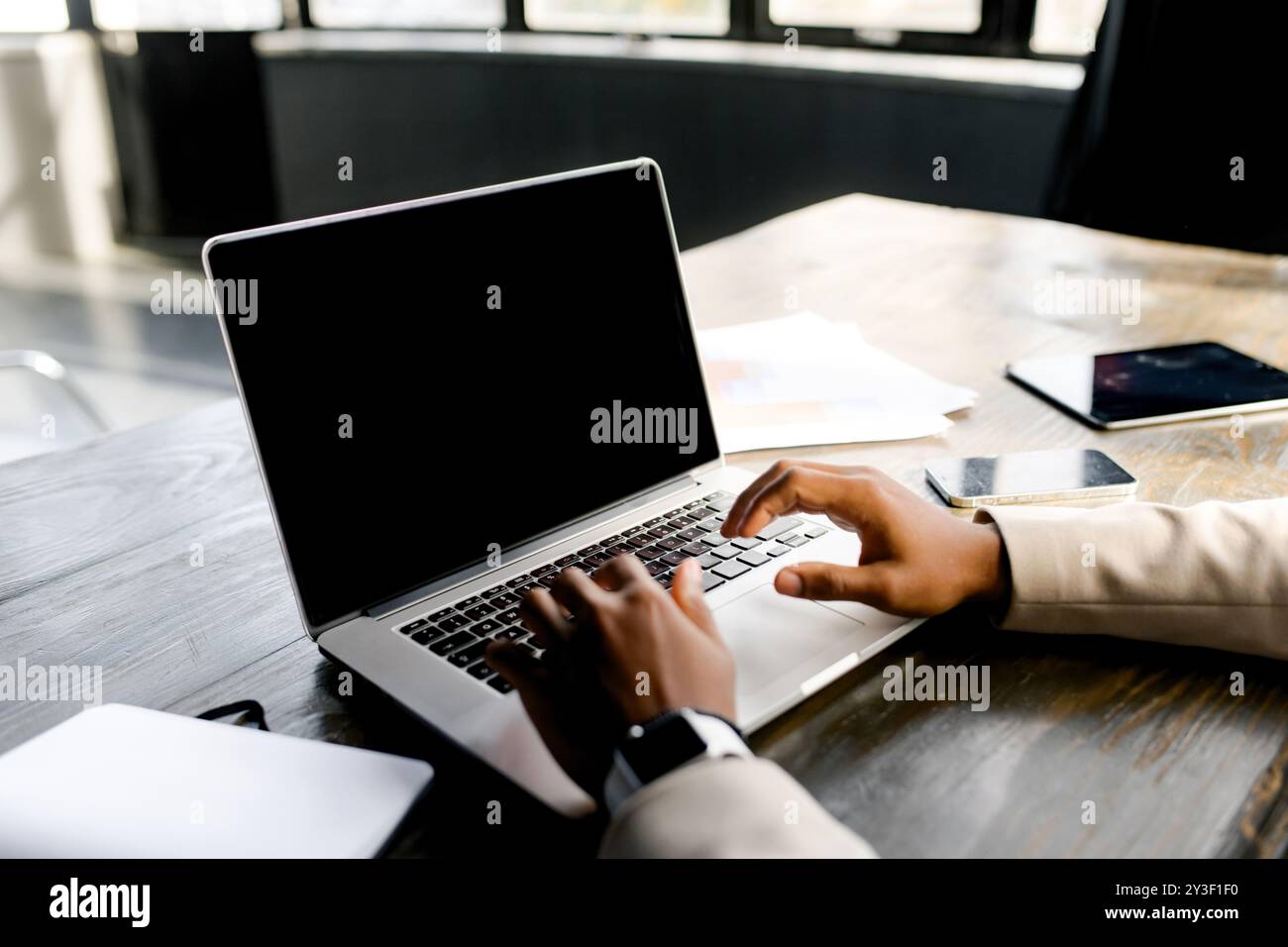 Un uomo d'affari viene catturato in un momento di concentrazione, lavorando sul suo laptop con uno schermo vuoto pronto per la pubblicità o per contenuti personalizzati Foto Stock