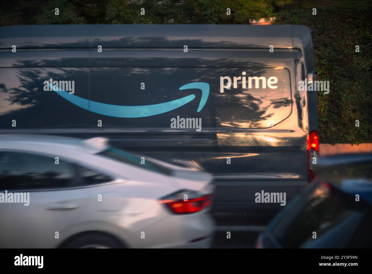 LOS ANGELES, CA - 13 marzo 2024: Camion di consegna Amazon prime che consegna pacchi in una trafficata strada residenziale di Hollywood al tramonto. Foto Stock