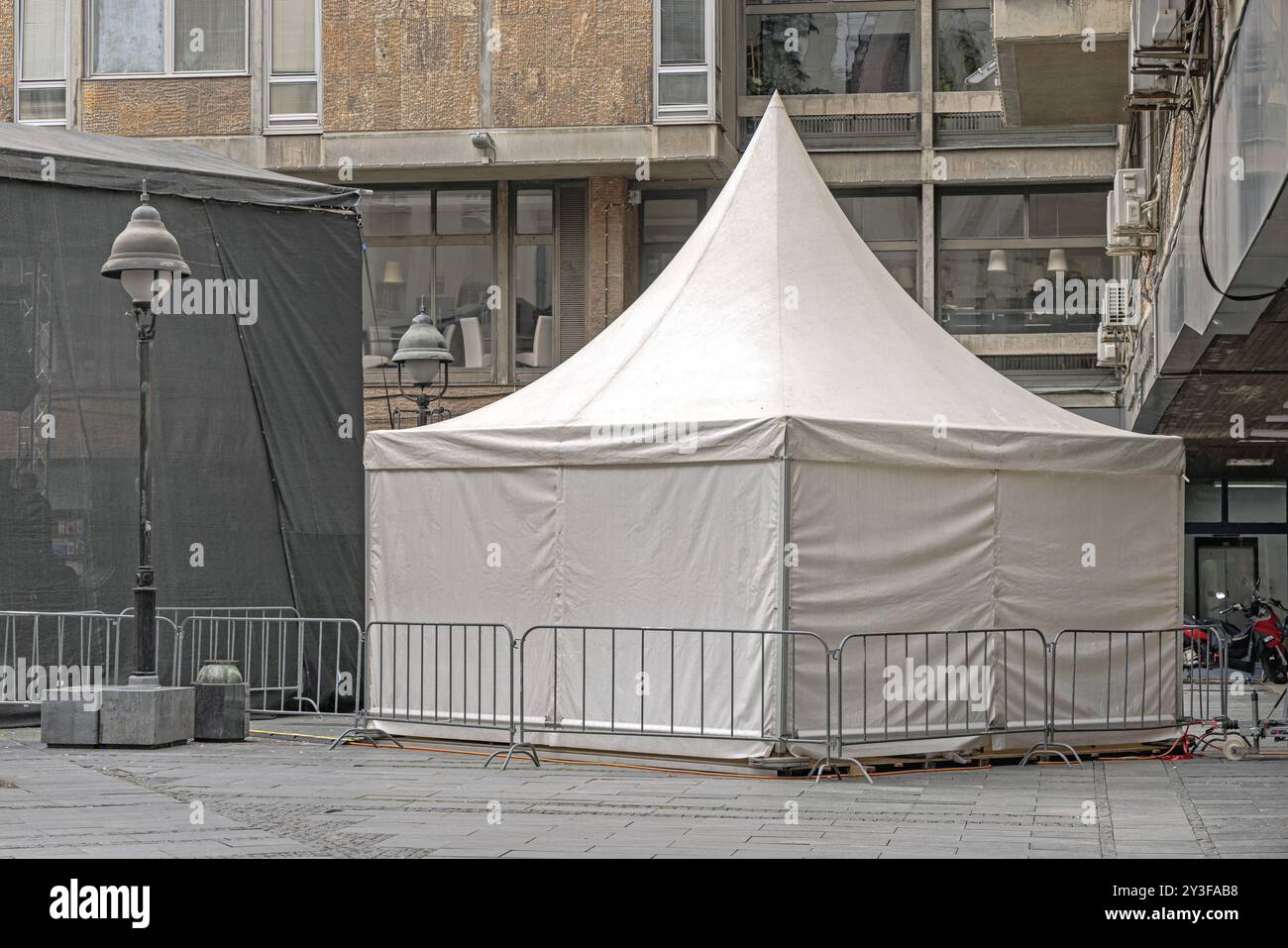 Struttura della tenda del baldacchino bianco con recinzione metallica dietro l'evento temporaneo del palco in Street in City Foto Stock