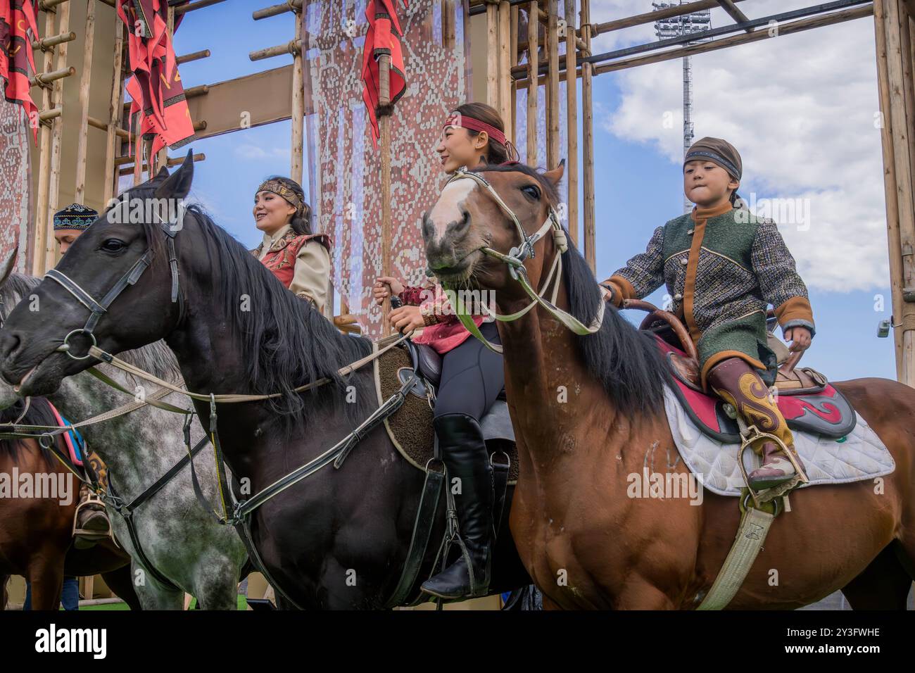 Le donne kazake e il ragazzo sui cavalli, in abiti tradizionali nomadi kazaki durante l'evento World Nomad Games ad Astana, Kazakistan Foto Stock
