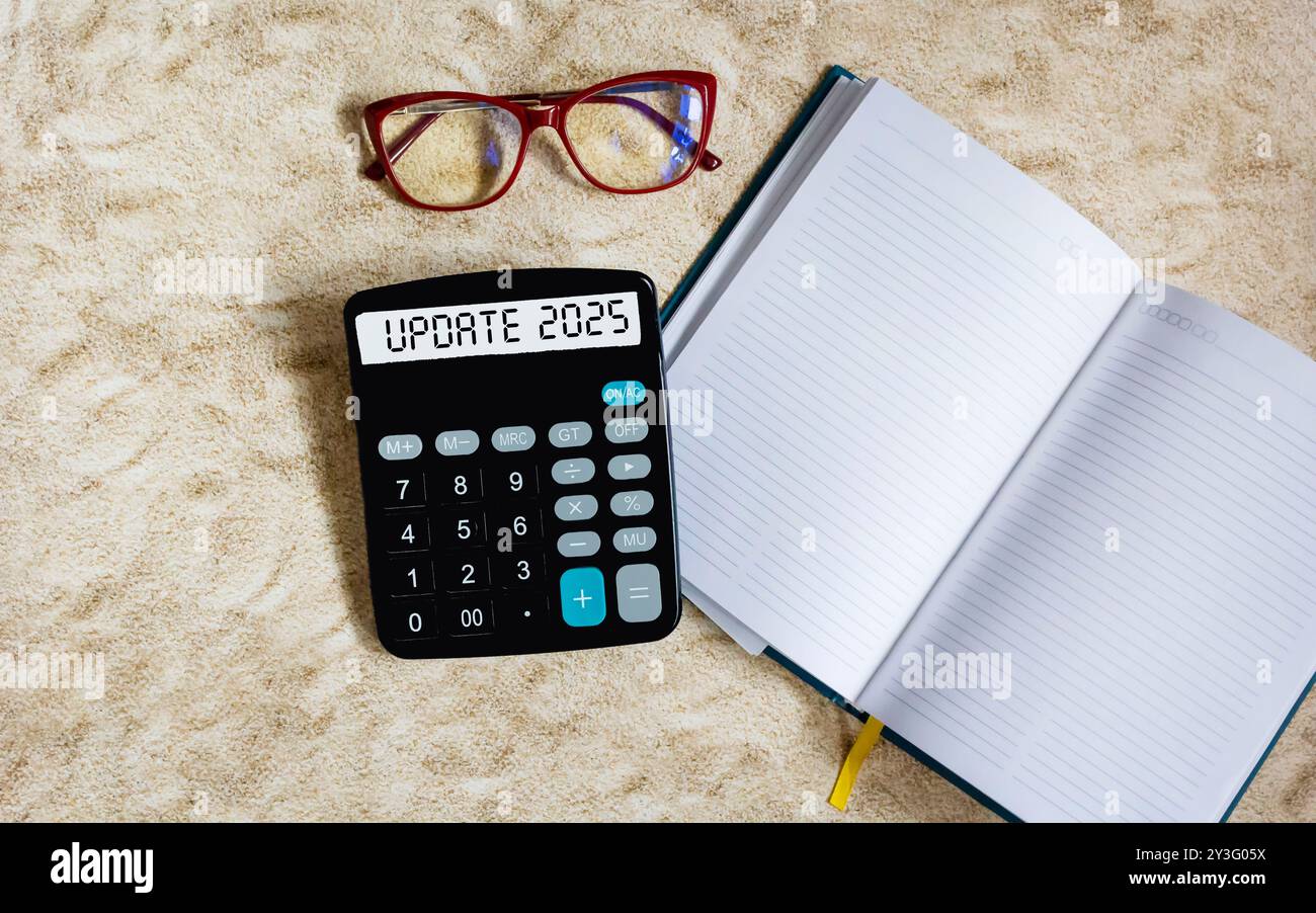2025 AGGIORNARE il testo sul display della calcolatrice. vicino al blocco note per la scrittura Foto Stock