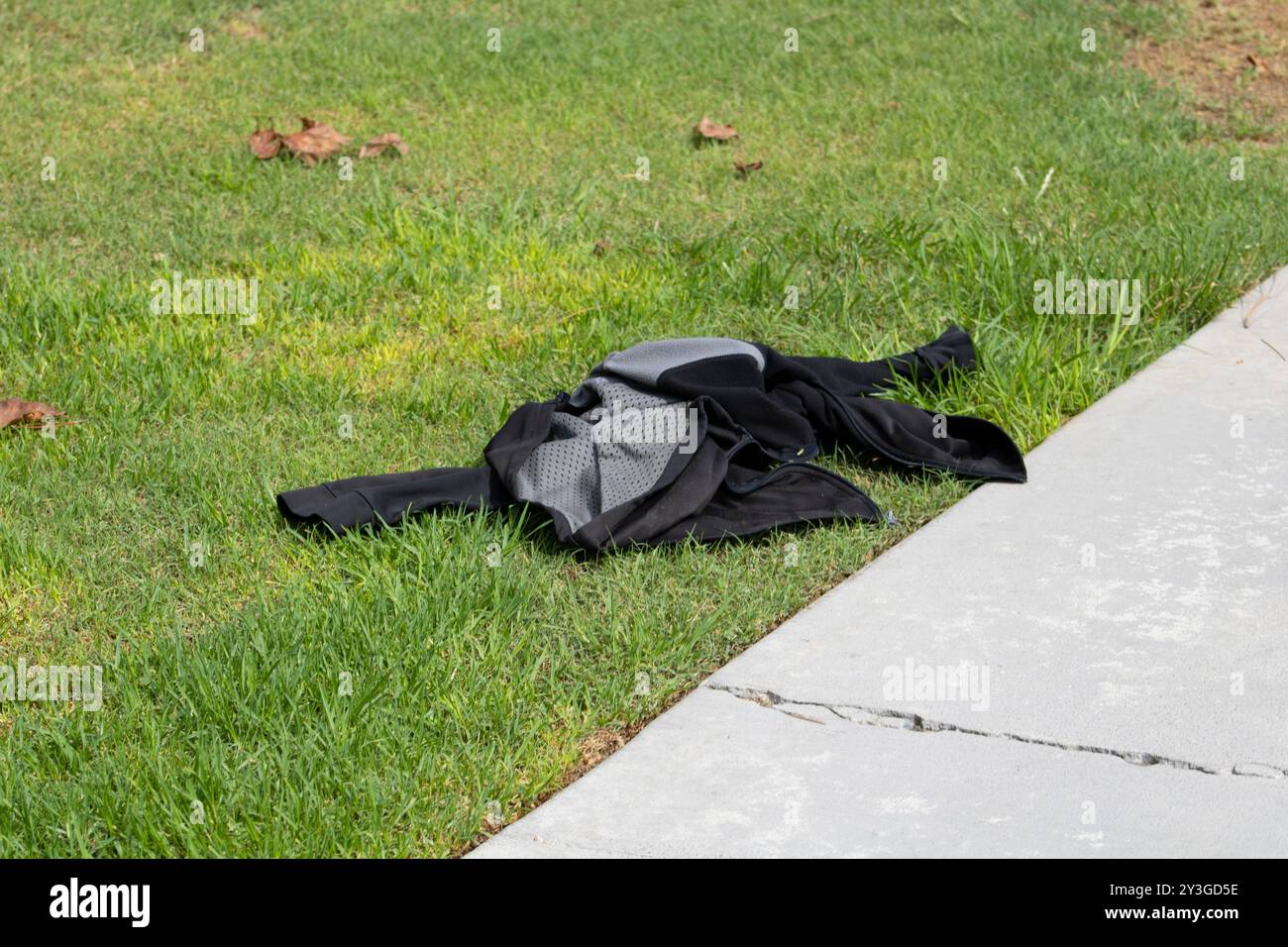 giacca nera e grigia rimasta stesa sull'erba Foto Stock