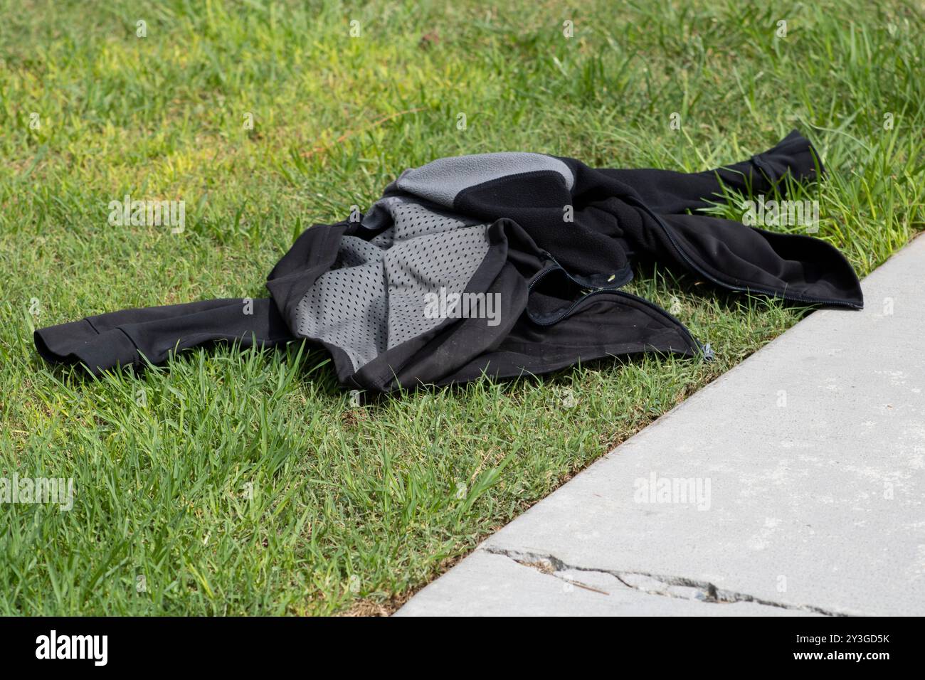 giacca nera e grigia rimasta stesa sull'erba Foto Stock