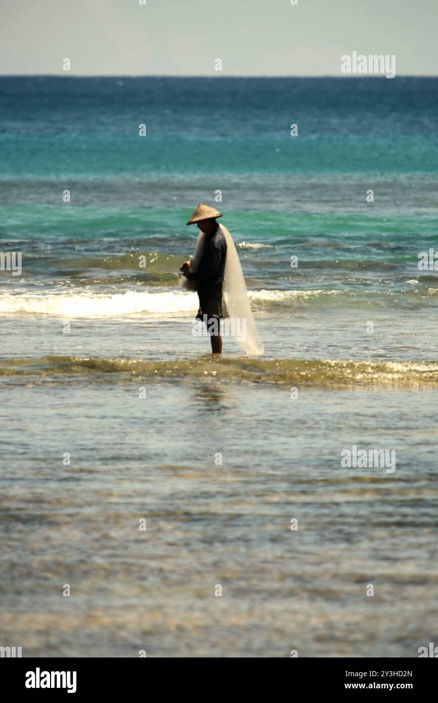 Un pescatore che prepara la rete da pesca per pescare sulle acque costiere della spiaggia di Tanjung Setia a Krui, Pesisir Barat, Lampung, Indonesia. Foto Stock