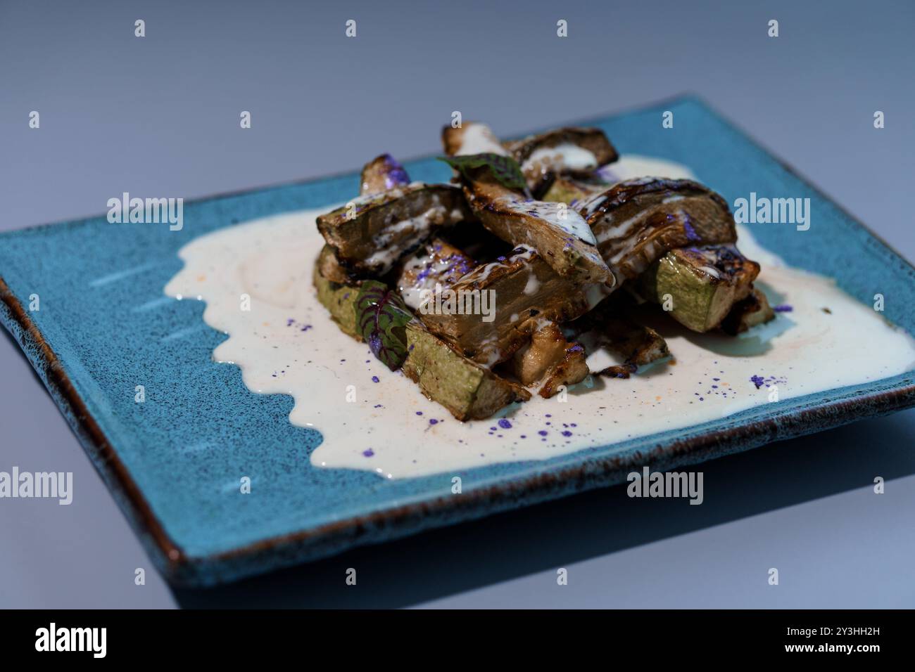 Melanzane gourmet con salsa cremosa su piatto in ceramica blu. Foto Stock