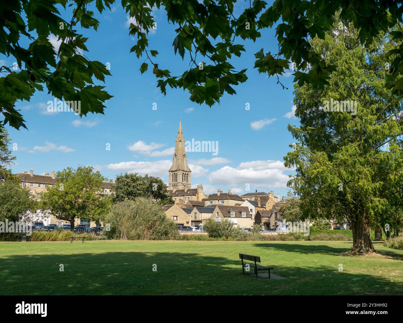 Guglia/torre della chiesa di St. Mary sopra i tetti degli edifici in pietra visti dai prati d'acqua di agosto, Stamford, Lincolnshire, Inghilterra, Regno Unito Foto Stock
