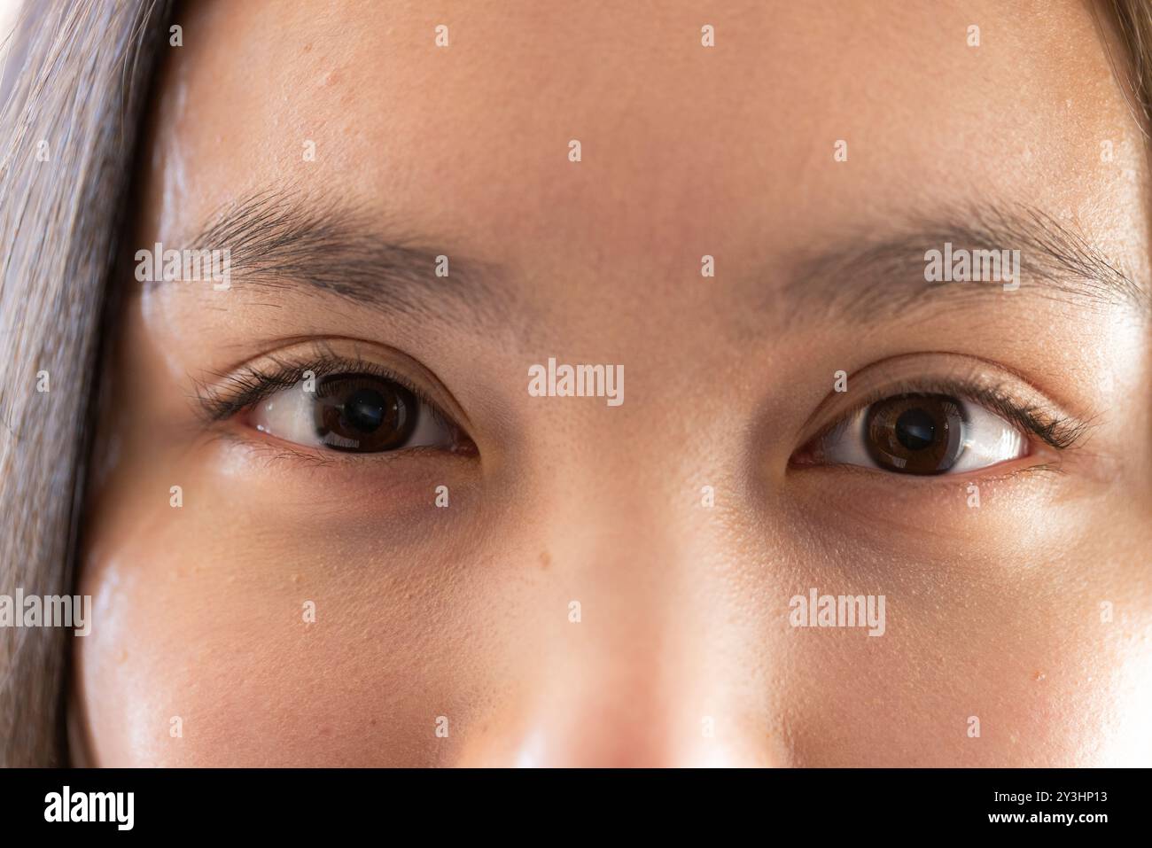 A casa, primo piano degli occhi di una giovane donna asiatica, concentrandosi sulle caratteristiche facciali e sull'espressione Foto Stock