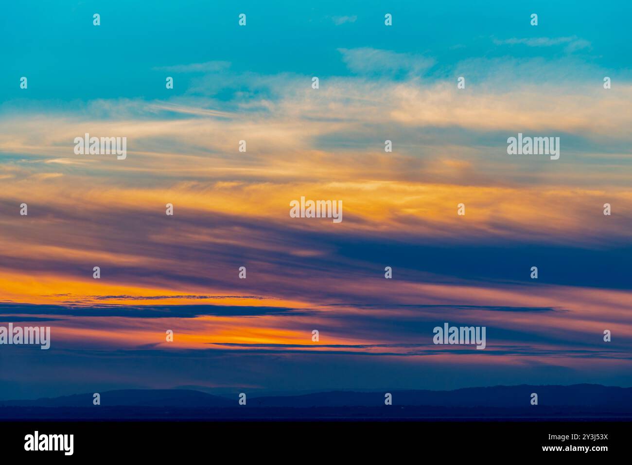 Il sole che tramonta illumina le nuvole con una leggera tonalità rossastro Foto Stock