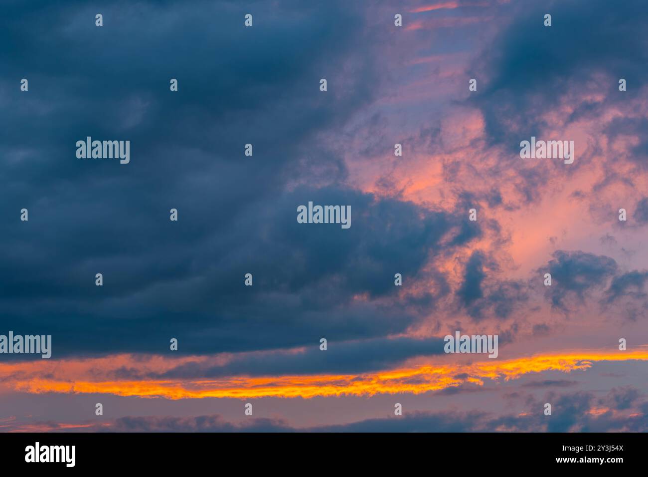 Il sole che tramonta illumina le nuvole con una leggera tonalità rossastro Foto Stock
