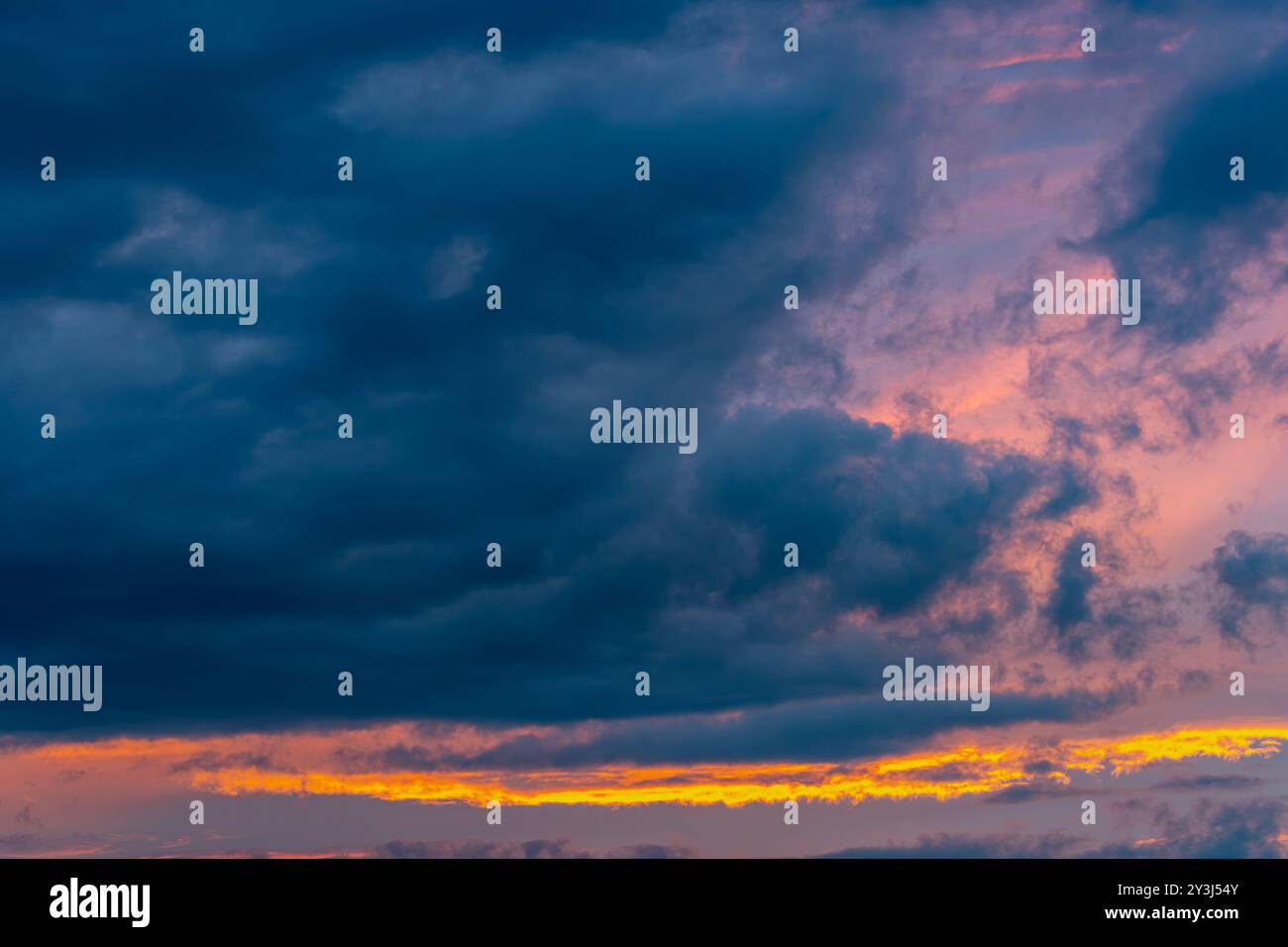 Il sole che tramonta illumina le nuvole con una leggera tonalità rossastro Foto Stock