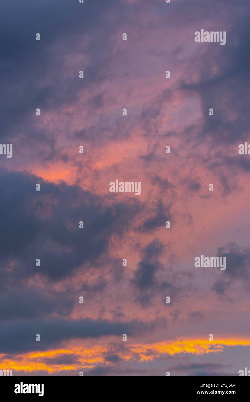 Il sole che tramonta illumina le nuvole con una leggera tonalità rossastro Foto Stock