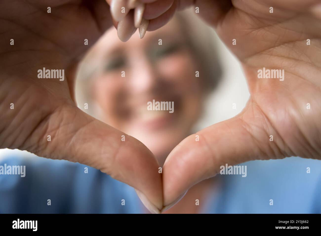 Primo piano vista ritagliata donna anziana che mostra simbolo d'amore Foto Stock