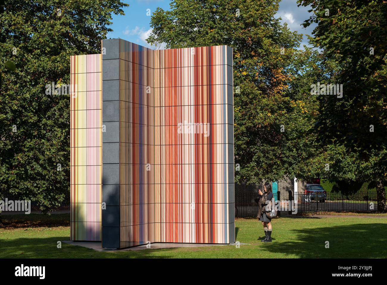 Installazione artistica della Strip Tower di Gerhard Richter all'esterno della Serpentine Gallery a Kensington Gardens, Londra, Regno Unito. Visita di una donna Foto Stock