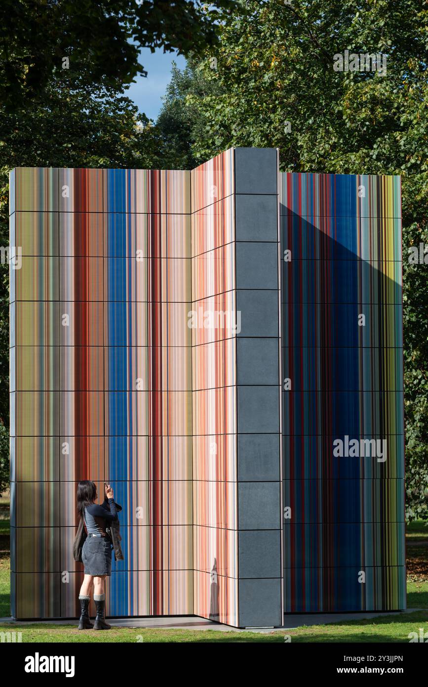 Installazione artistica della Strip Tower di Gerhard Richter all'esterno della Serpentine Gallery a Kensington Gardens, Londra, Regno Unito. Visita di una donna Foto Stock