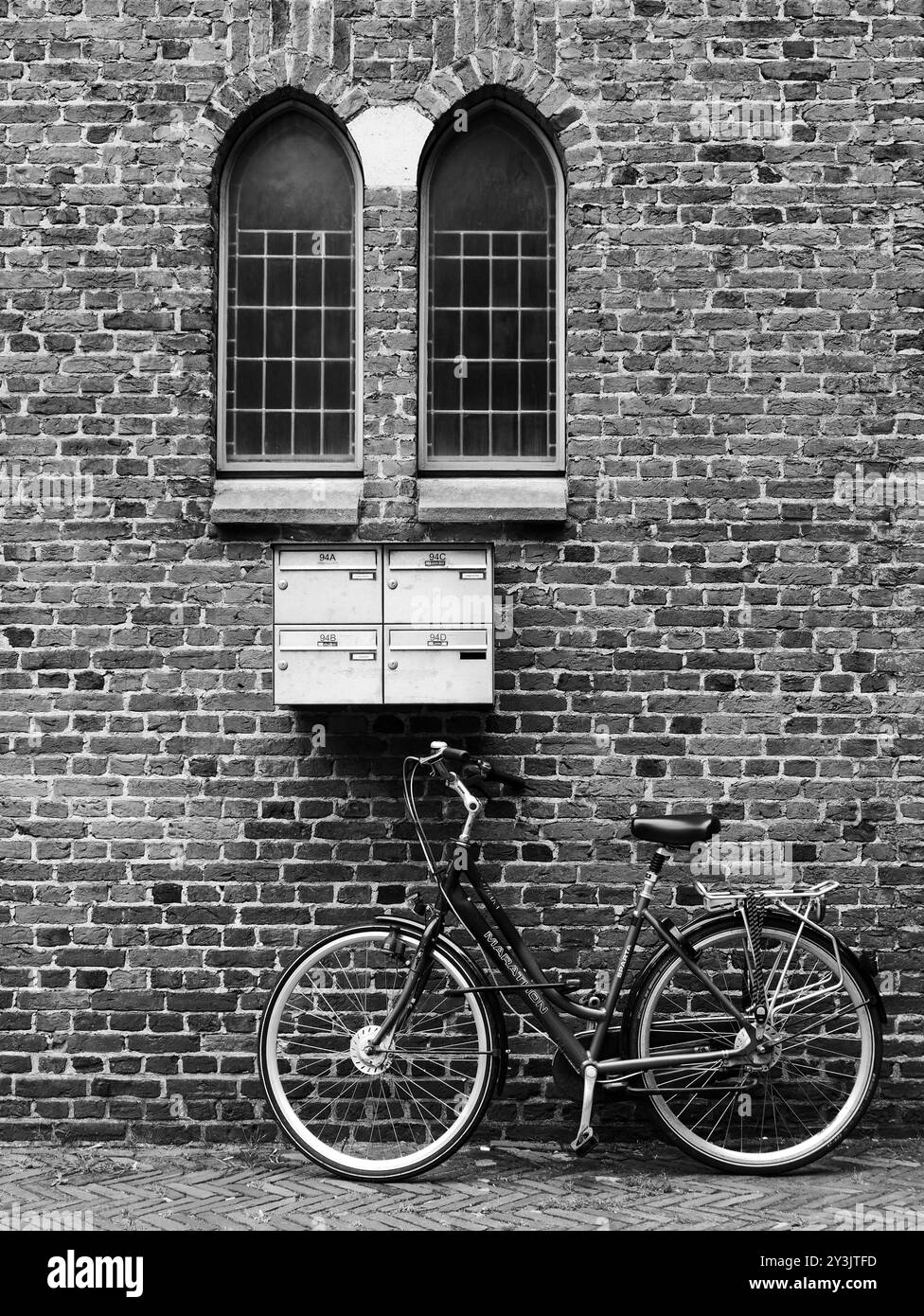 Linee simmetriche di una bicicletta parcheggiata accanto a una chiesa sotto una cassetta postale con spazio libero Foto Stock