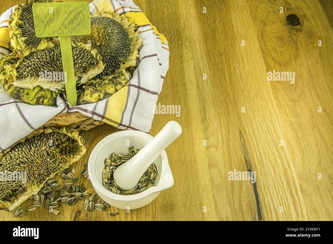 Mortaio bianco con pestello e semi di girasole schiacciati all'interno, in ambiente autunnale Foto Stock