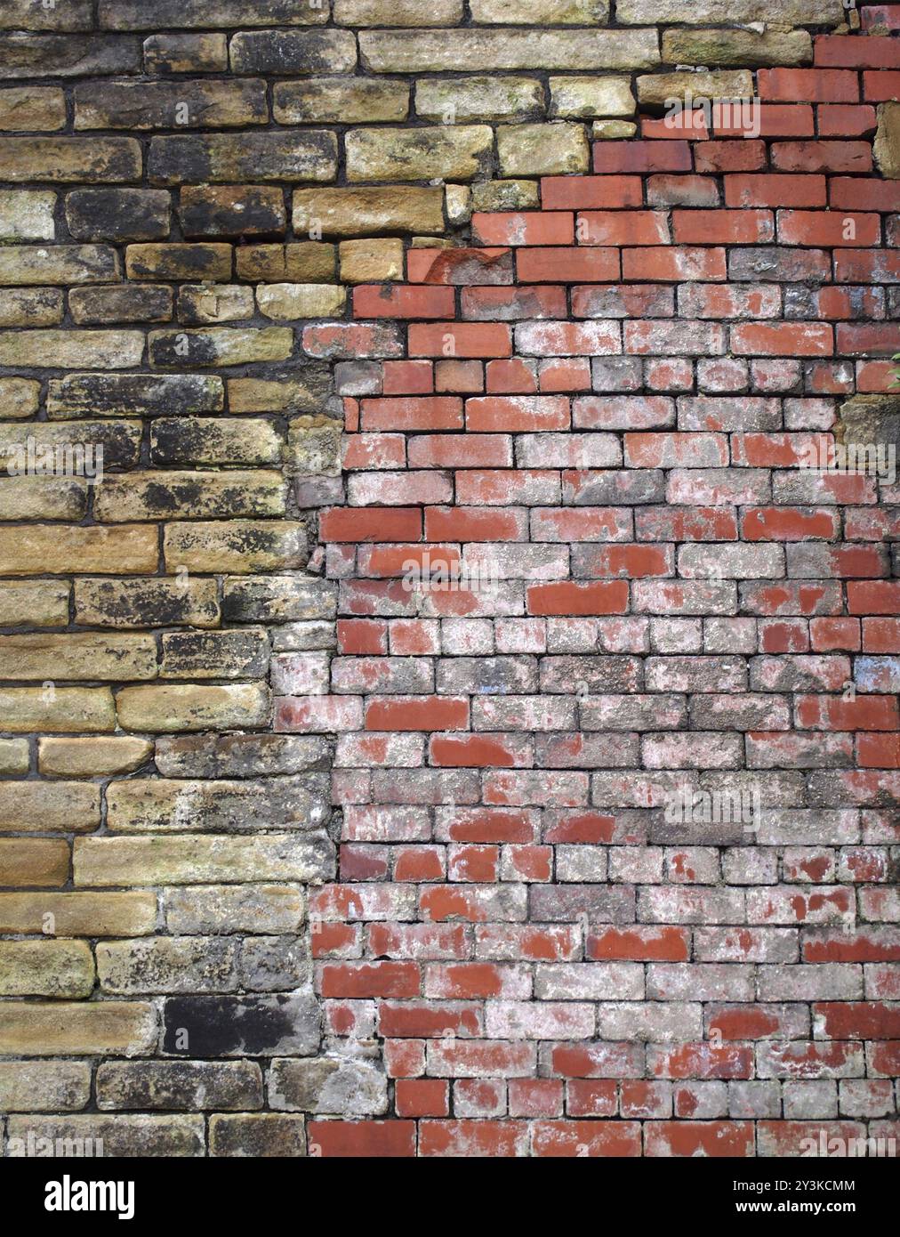 Un vecchio muro esterno riparato, fatto di pietra e ricoperto di mattoni Foto Stock