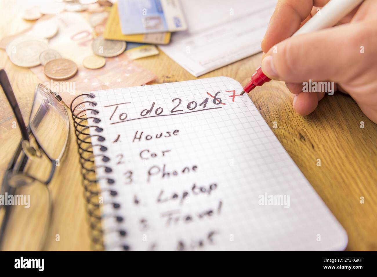 Close-up immagine con i piani finanziari per il 2017, scritto da una mano d'uomo nel marcatore su un notebook a spirale, denaro, carte di credito e le fatture sono in background Foto Stock