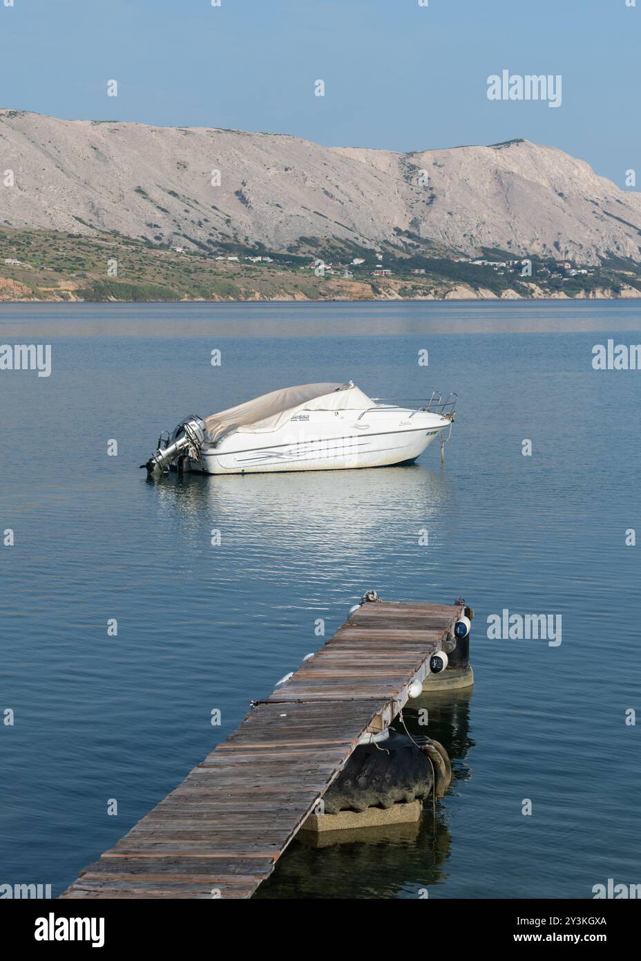 Barca ormeggiata in mare, terra con case in lontananza Foto Stock