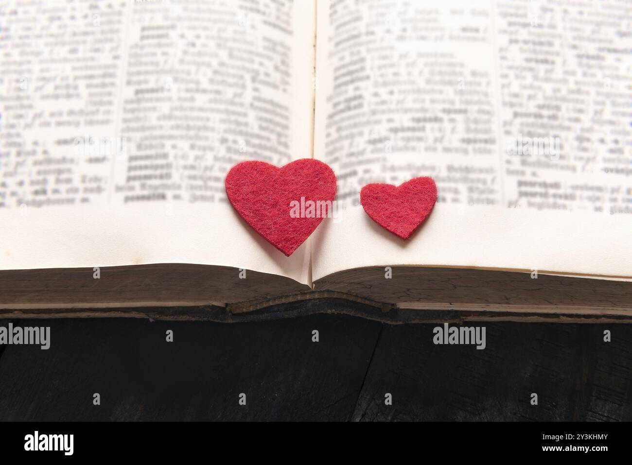 Close-up immagine con due cuori rossi collocato su un vecchio libro aperto, su di un tavolo di legno. Un concetto di lettura, di apprendimento, di educazione o di una storia di amore, roma Foto Stock