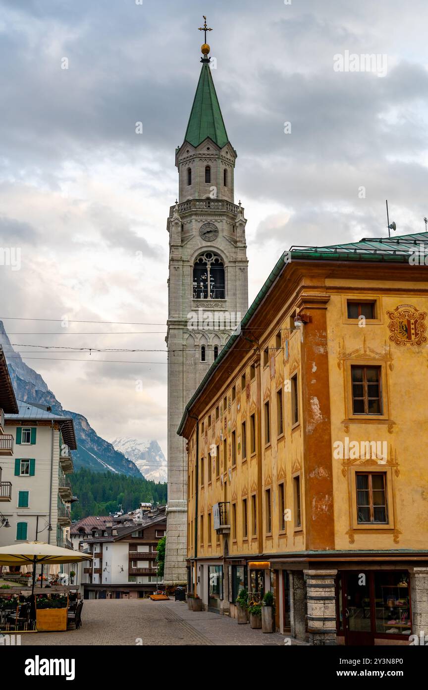 Una vista dell'iconica torre della chiesa nel cuore di Cortina d'Ampezzo. La bellezza architettonica della torre si erge alto sullo sfondo del sur Foto Stock