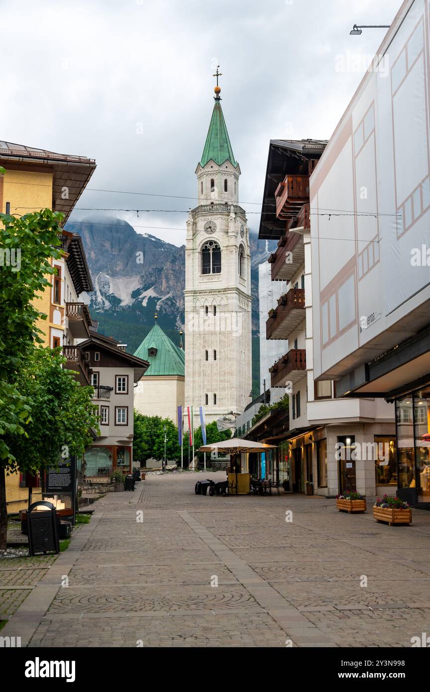 Una vista dell'iconica torre della chiesa nel cuore di Cortina d'Ampezzo. La bellezza architettonica della torre si erge alto sullo sfondo del sur Foto Stock