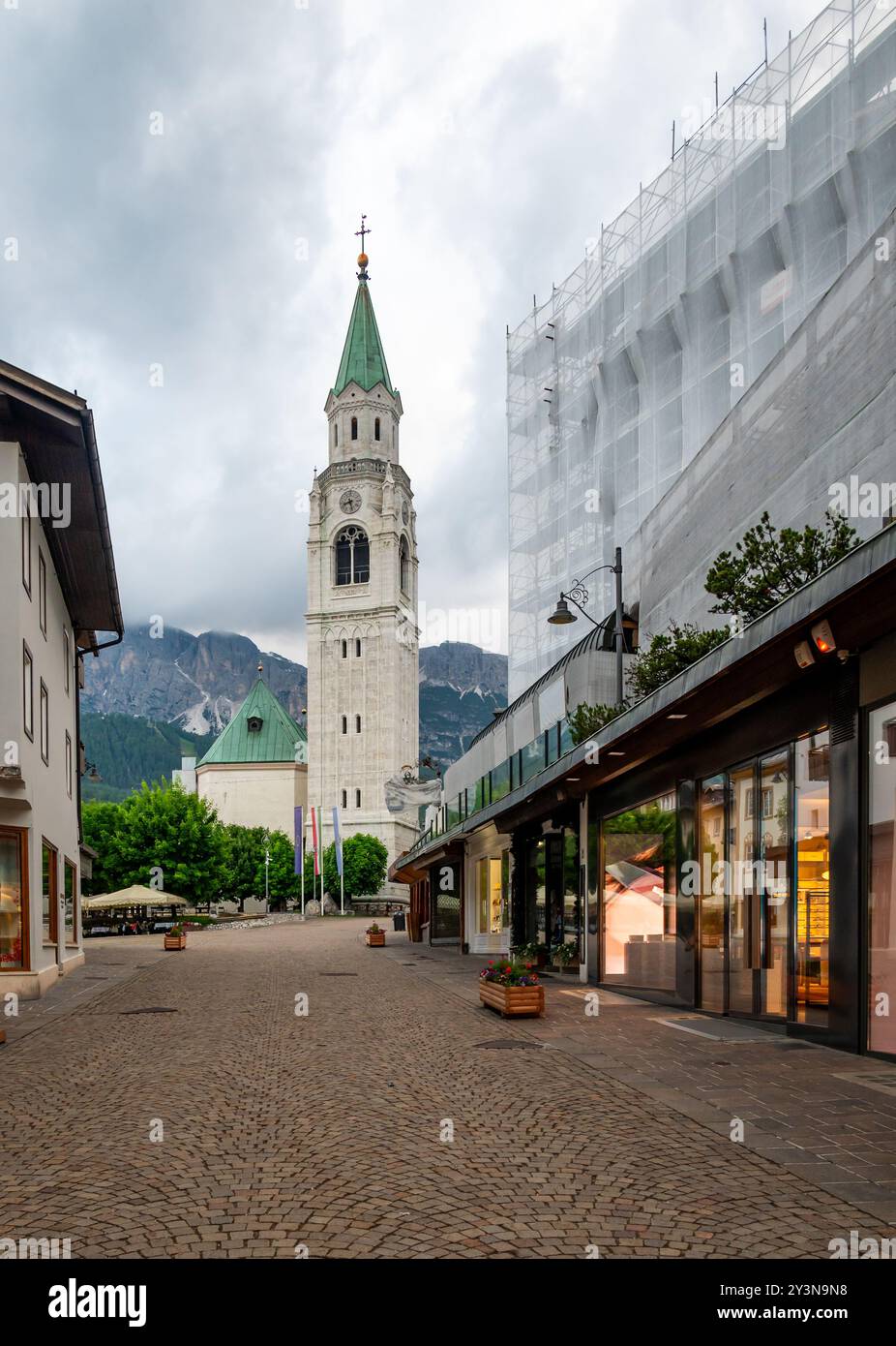Una vista dell'iconica torre della chiesa nel cuore di Cortina d'Ampezzo. La bellezza architettonica della torre si erge alto sullo sfondo del sur Foto Stock