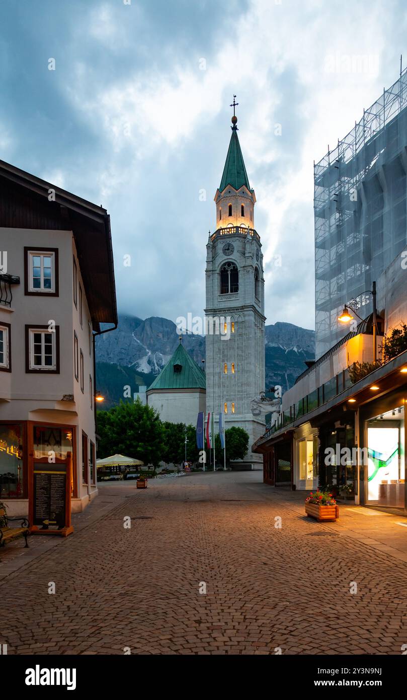 Una vista dell'iconica torre della chiesa nel cuore di Cortina d'Ampezzo. La bellezza architettonica della torre si erge alto sullo sfondo del sur Foto Stock