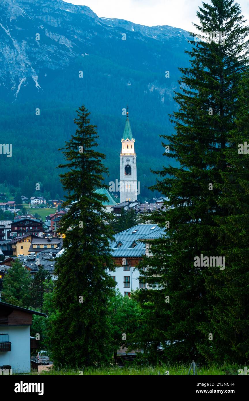Una vista dell'iconica torre della chiesa nel cuore di Cortina d'Ampezzo. La bellezza architettonica della torre si erge alto sullo sfondo del sur Foto Stock