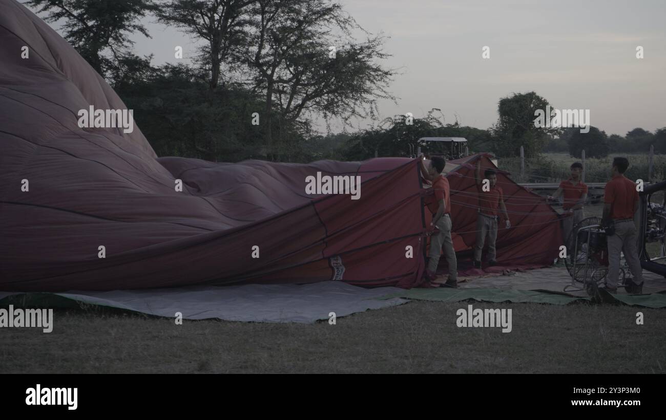 Lavoratori che preparano le mongolfiere all'alba per le mongolfiere su Bagan alla luce del mattino presto Foto Stock