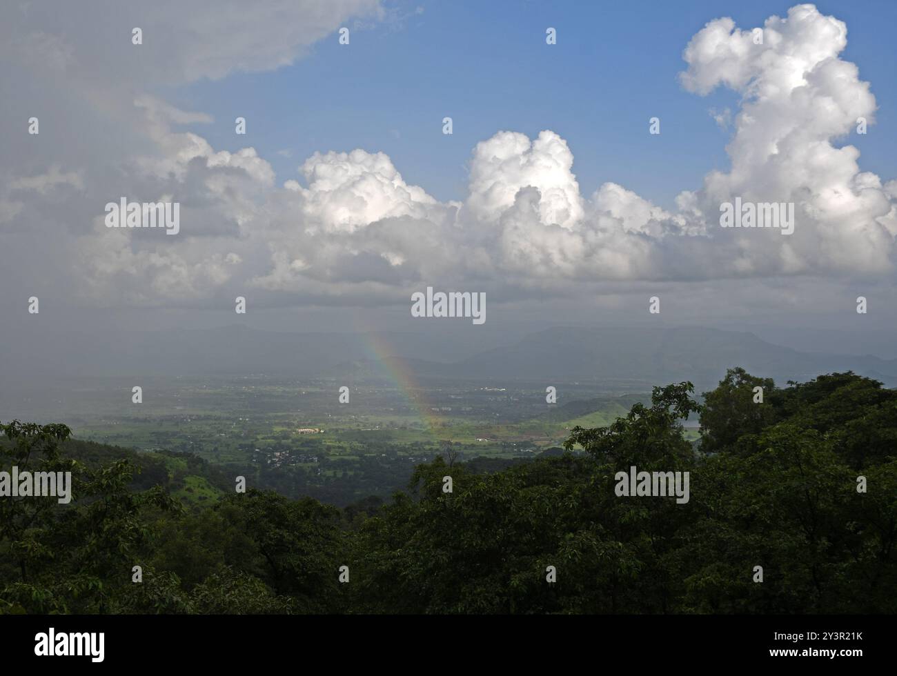 Un arcobaleno si forma vicino alla città di Neral sotto della stazione collinare di Matheran nel distretto di Raigad alla periferia di Mumbai. Matheran è una splendida stazione collinare situata alla periferia della città nel quartiere Raigad di Maharashtra. i veicoli a motore sono vietati nella stazione della collina e i turisti possono prendere un treno giocattolo che va proprio all'interno della stazione della collina da dove i turisti possono camminare o noleggiare un risciò trainato a mano o andare a cavallo per visite turistiche all'interno e intorno alla stazione della collina. i mesi monsonici sono preferiti dai turisti in quanto l'intera stazione collinare si trasforma in un tappeto verde a causa della pioggia. Foto Stock